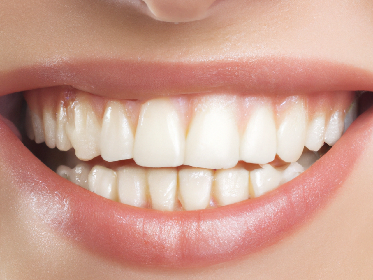 Home A detailed close-up of a perfect set of white teeth and lips in a bright smile.