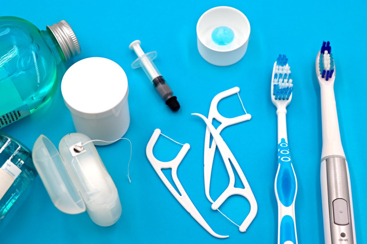 Home A variety of dental hygiene tools arranged neatly on a vibrant blue surface, showcasing oral care essentials.