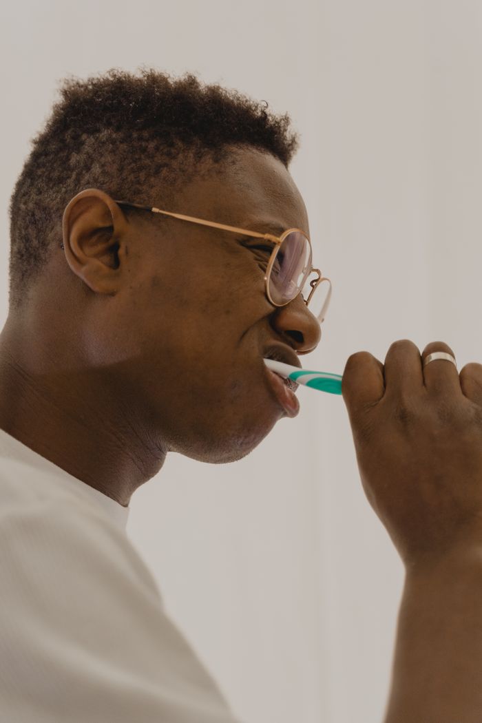Home Side view of a young man brushing his teeth, promoting daily oral hygiene habits.
